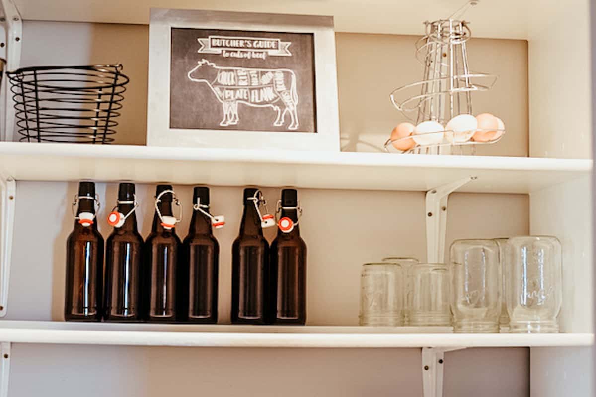 empty glass bottles on white pantry shelves