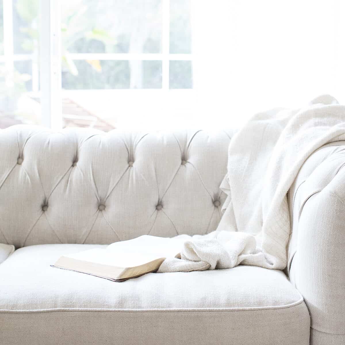 white couch with an open bible and blanket