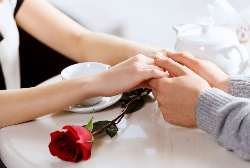 romantic date night with a red rose and hand holding couple