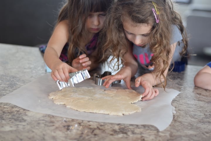 girls cutting out cookies with a cookie cutter