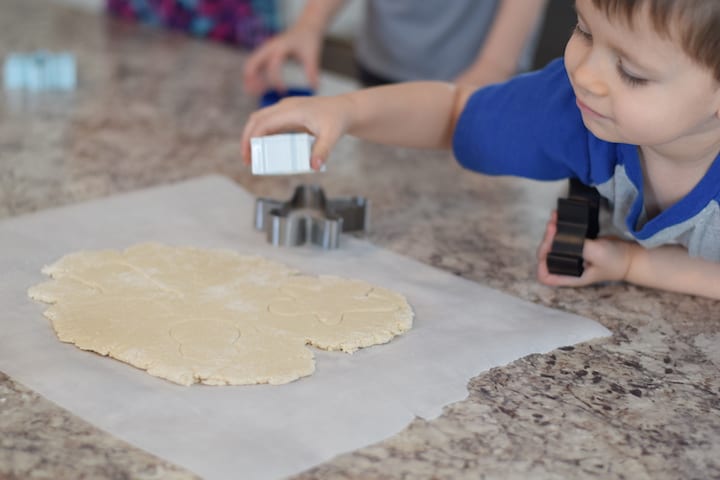 little boy helping cut out cookie shapes