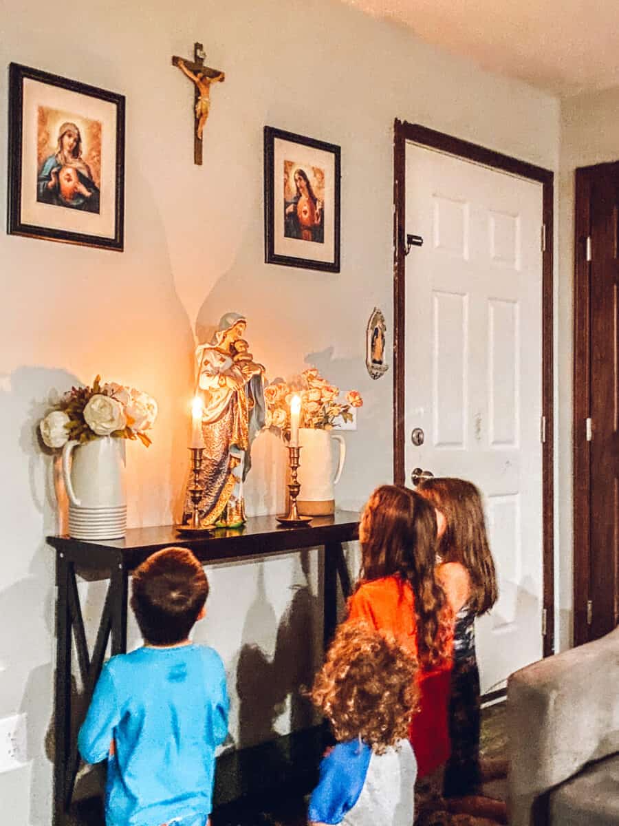 children praying the rosary in front of the catholic home altar