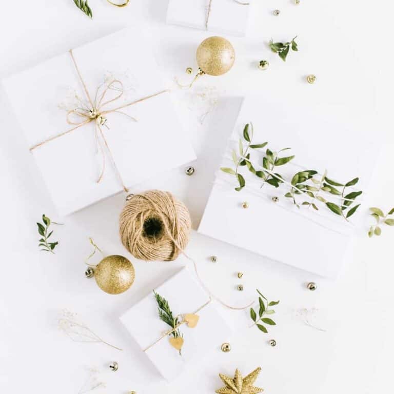 stack of white gifts tied with twine and greenery