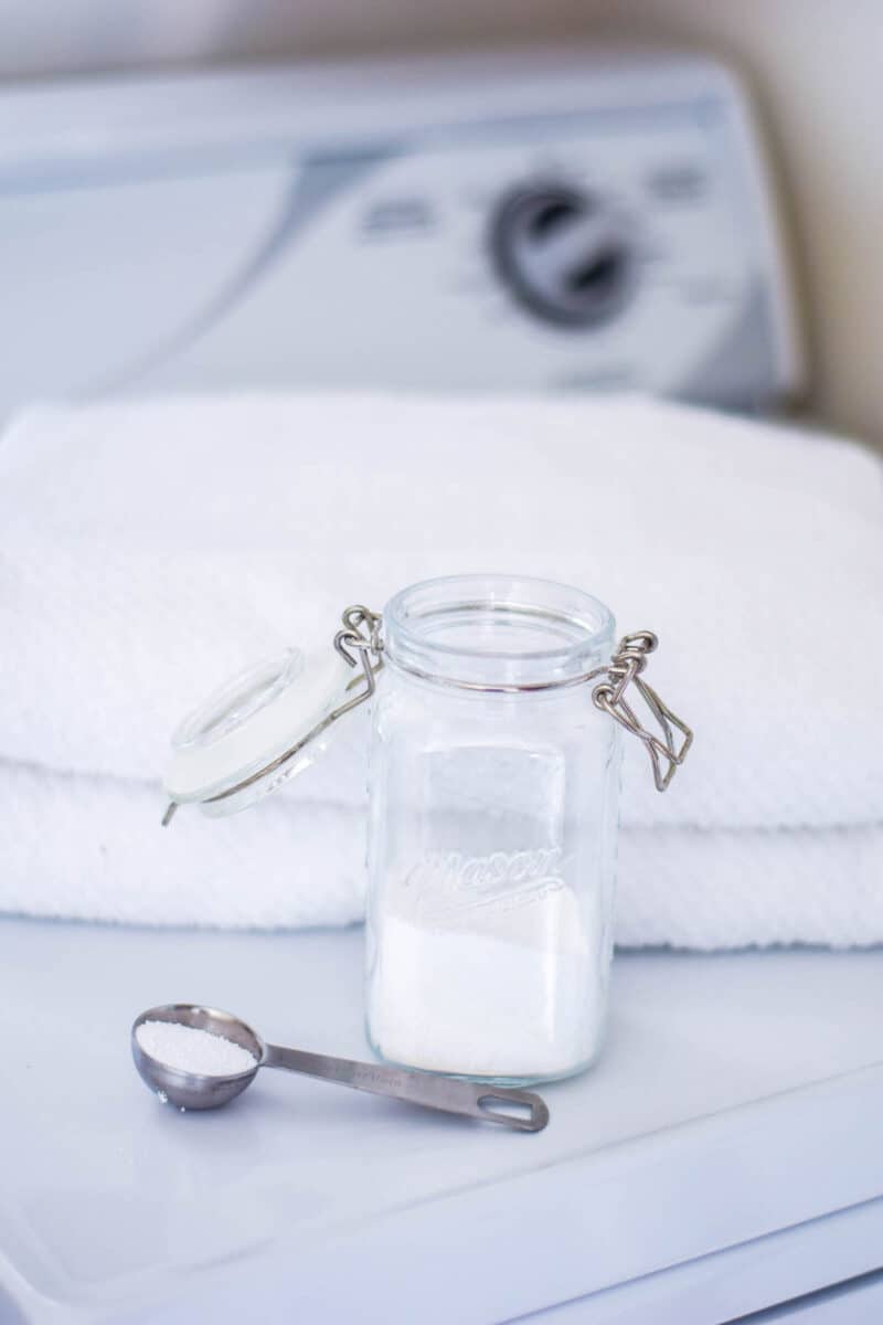 white towels folded on dryer with a mason jar of powdered detergent with measuring spoon