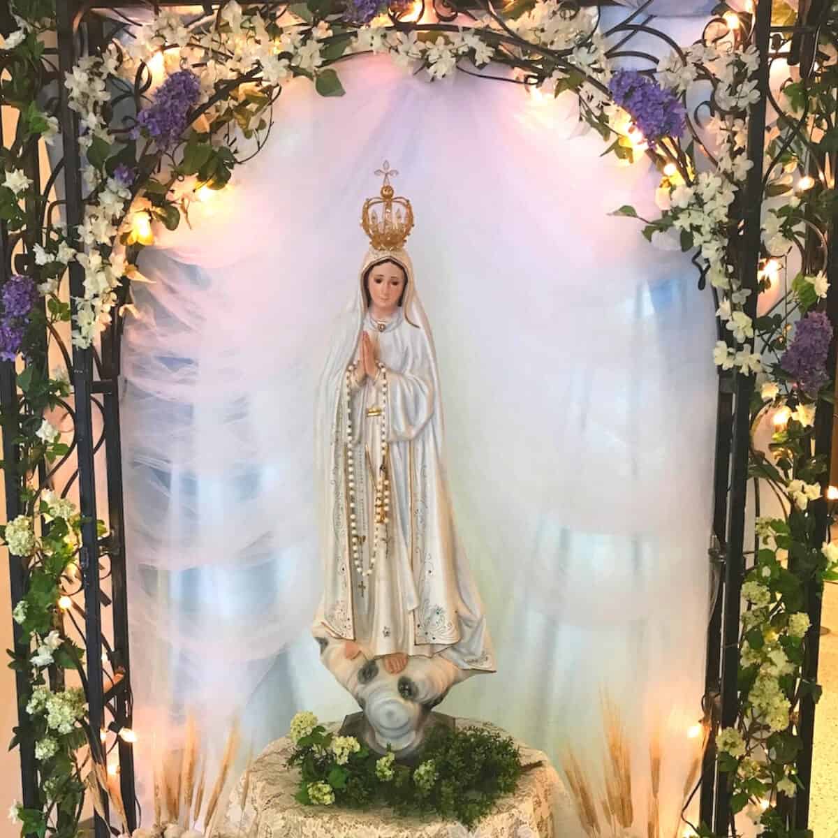 blessed mother statue with flowers in an arch around the statue