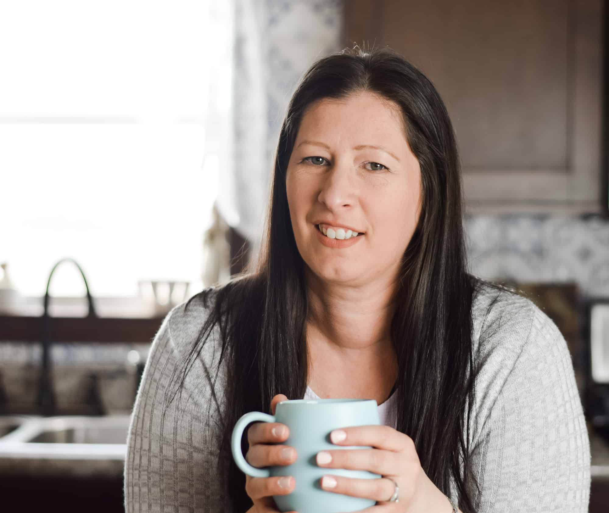 holding a blue cup of coffee in the kitchen