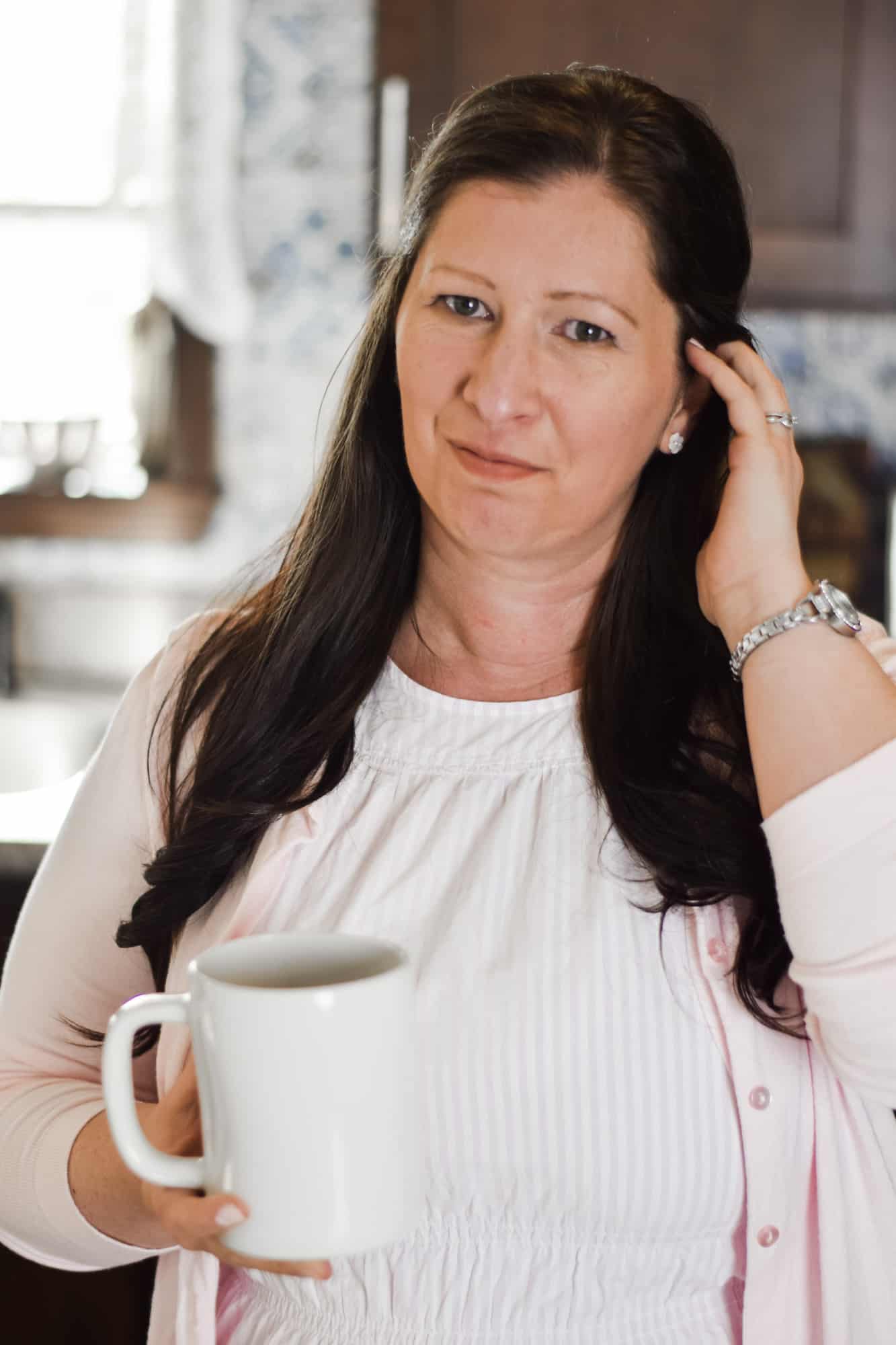 headshot of Mary in the kitchen with a cup of coffee