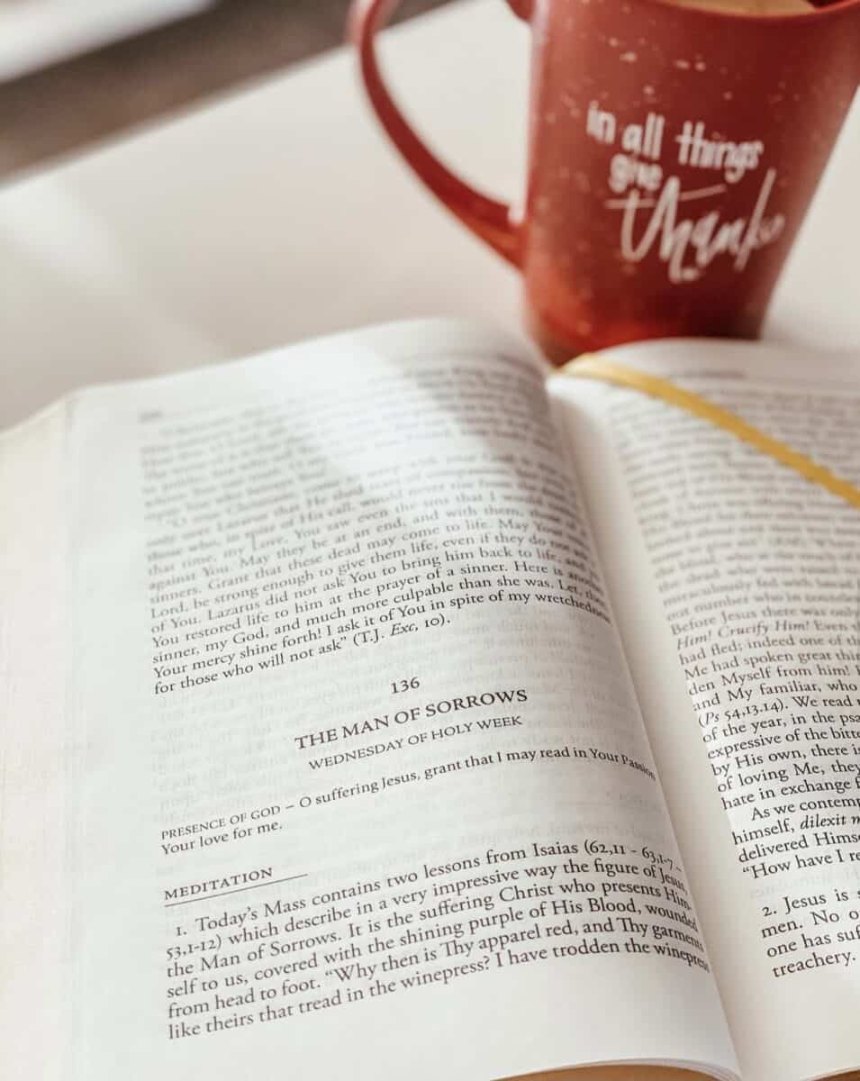 Divine Intimacy book open with a coffee cup in the background