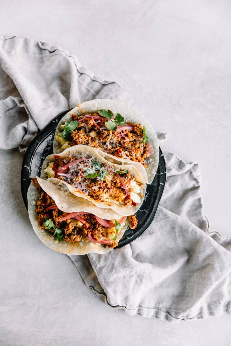 3 tacos on a plate with a variety of toppings