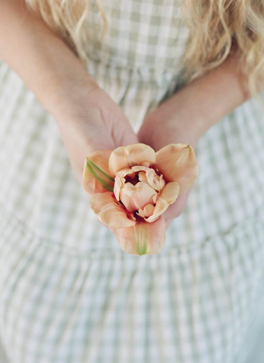 lady in white checkered dress holding flowers.