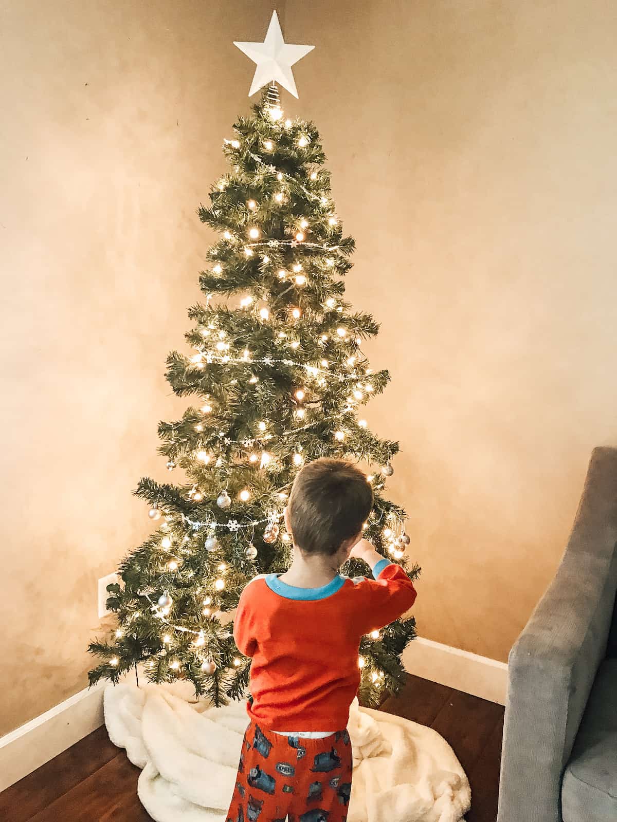 little boy standing in front of the decorated Christmas tree.