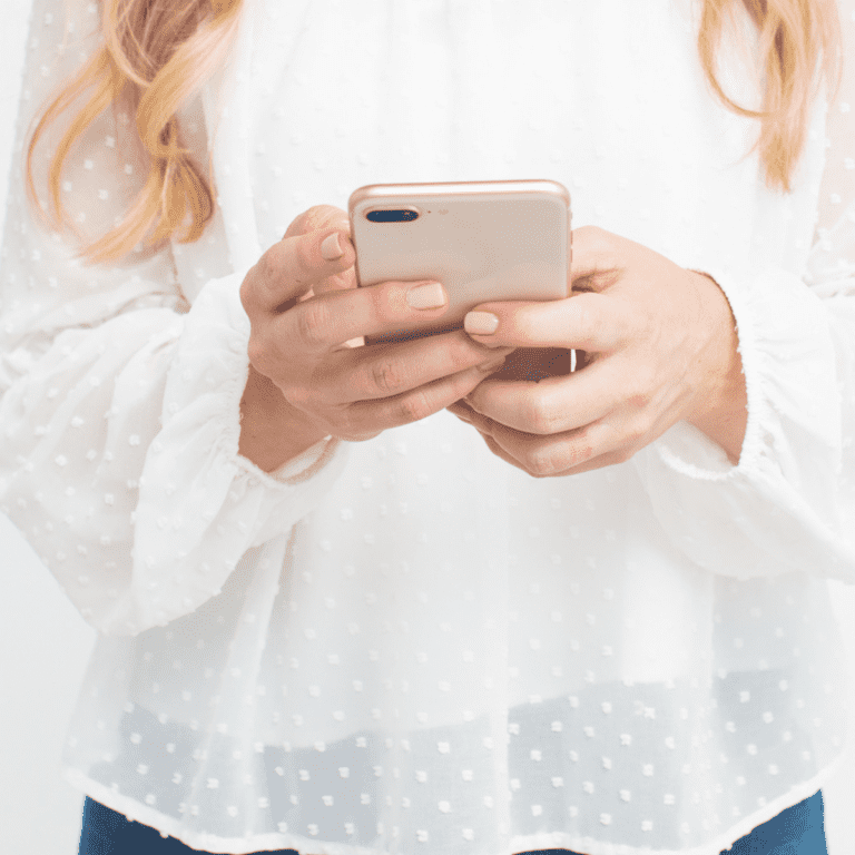 woman in a white flowy blouse holding a smartphone