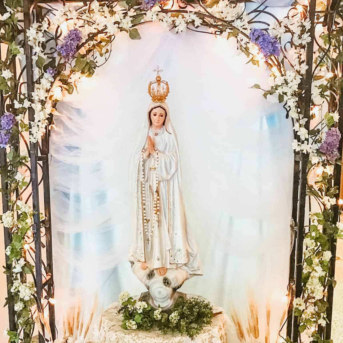statue of Our Lady of Fatima with an archway of flowers surrounding it.