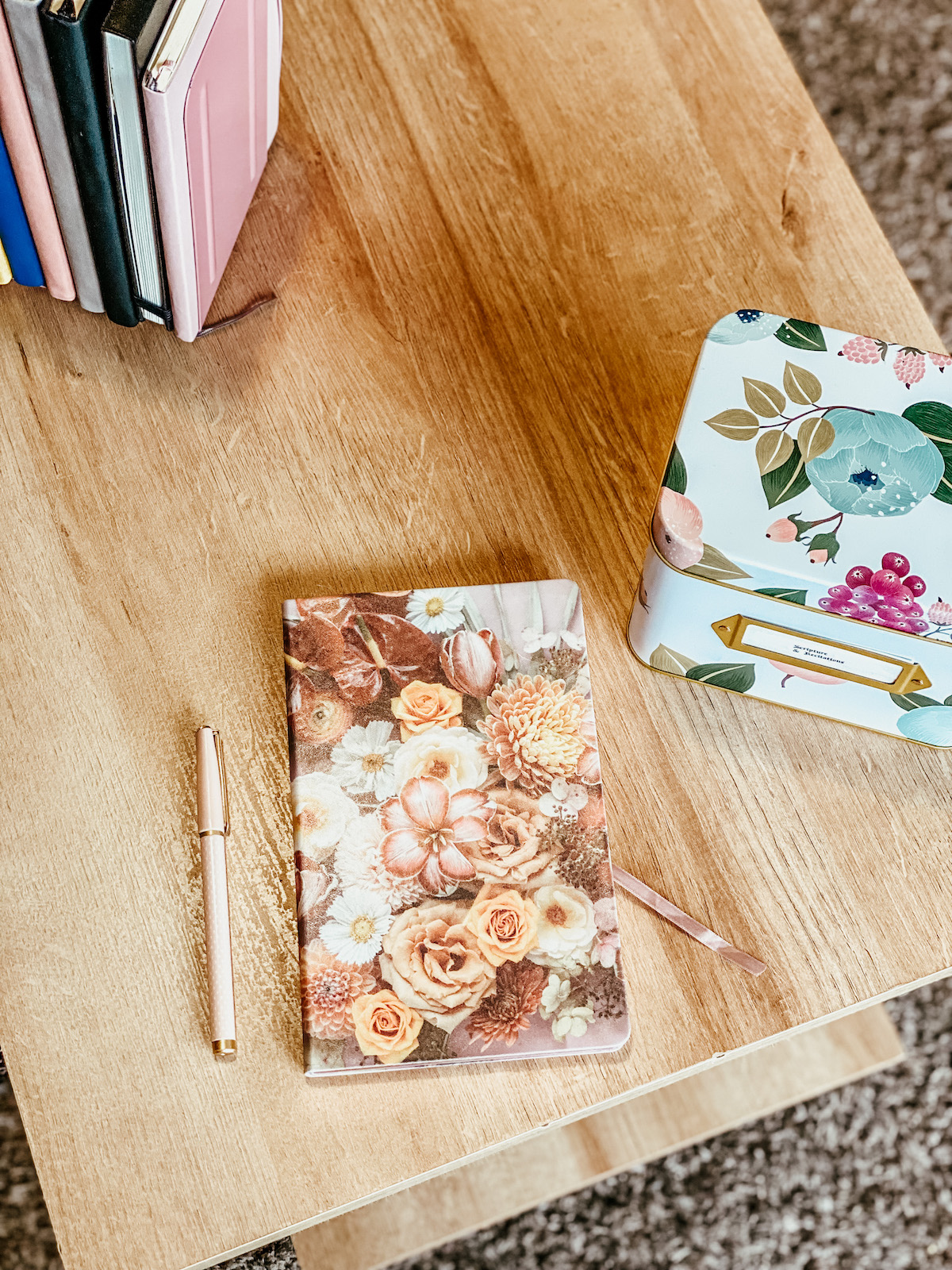 floral journal notebook with a light pink pen to the side on a table.