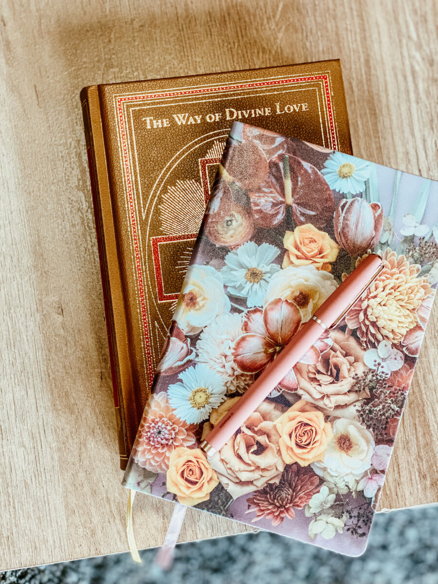 The Way of Divine Love book with a floral notebook on top with a light pink pen.