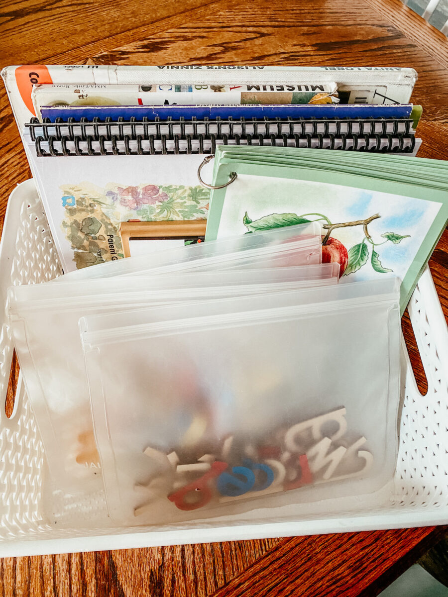 white bin filled with picture books, wooden letters, and other preschool reading supplies