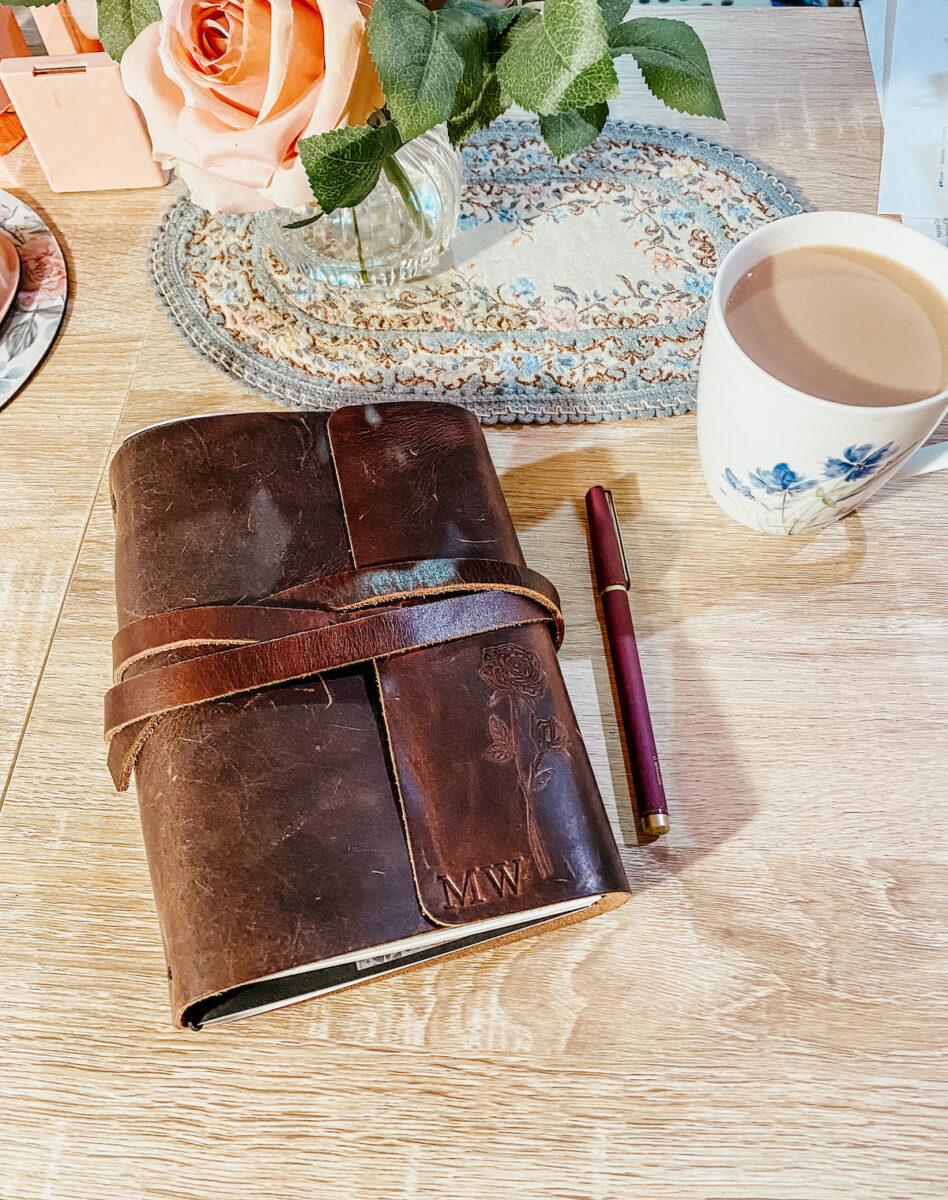 mother’s leather journal on a desk with a cup of coffee to the side.