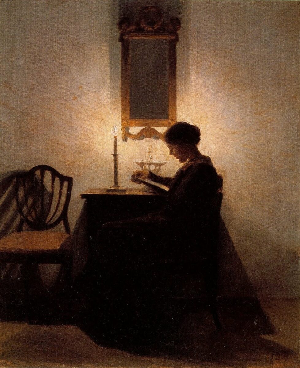 lady sitting by candlelight and reading.