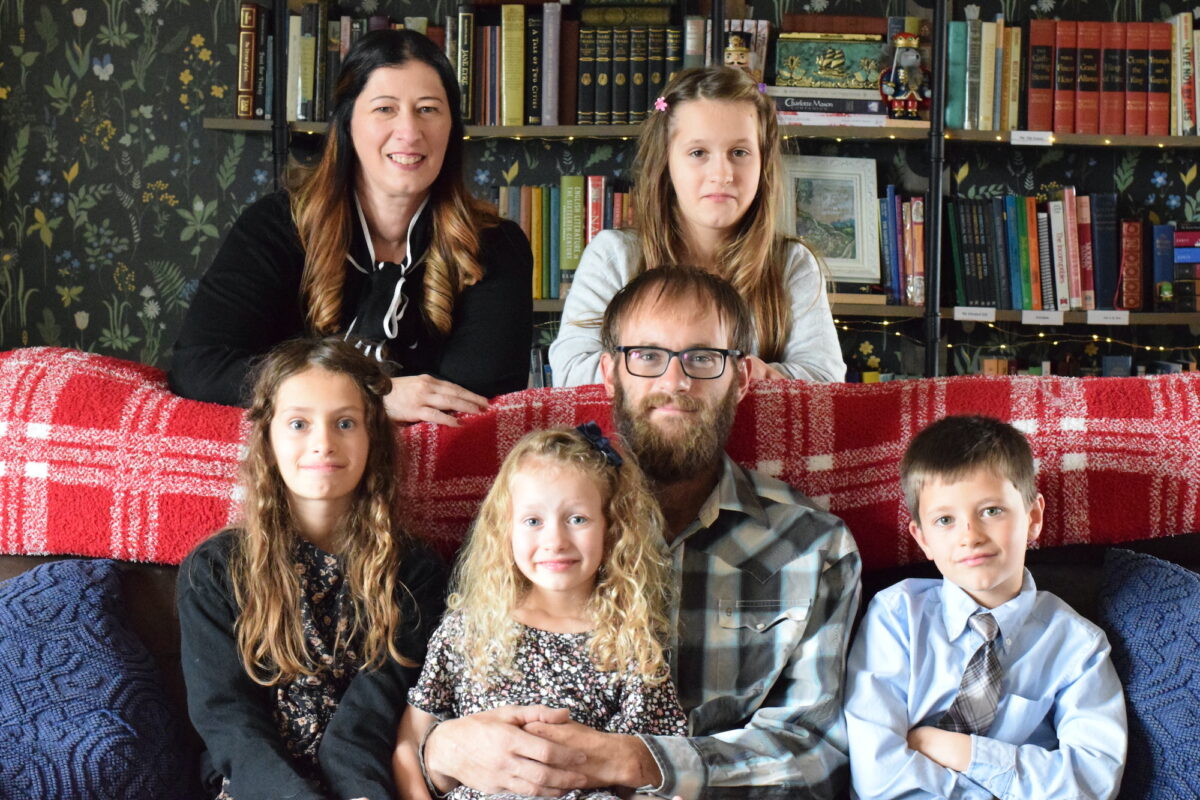 family picture sitting on the couch in front of the library shelves.