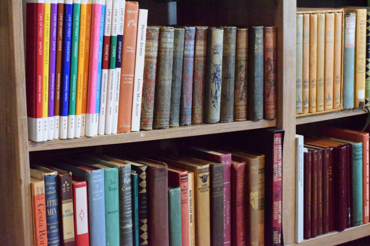 school books and other vintage books on a book shelf. 