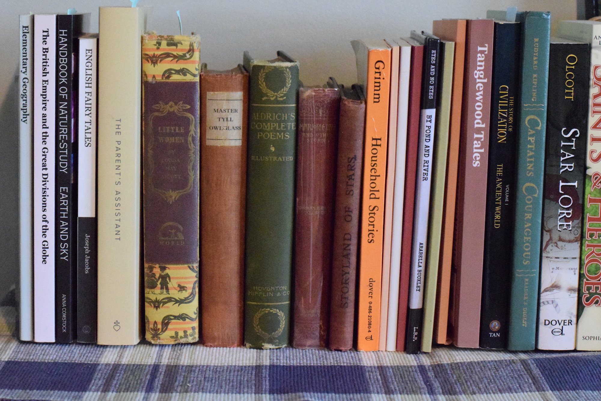 variety of school books stacked on top of a bookshelf.