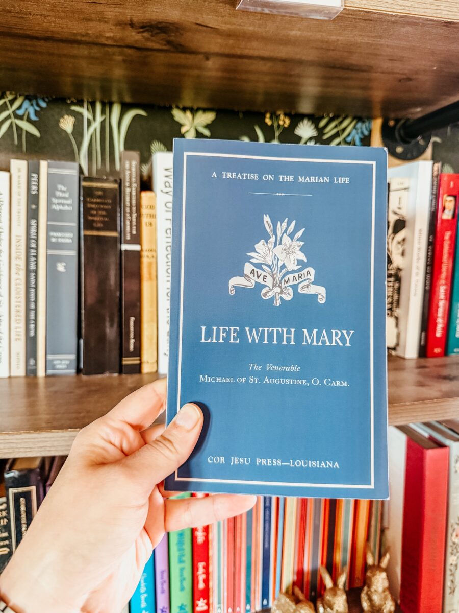 Life with Mary book held in front of a bookshelf. 