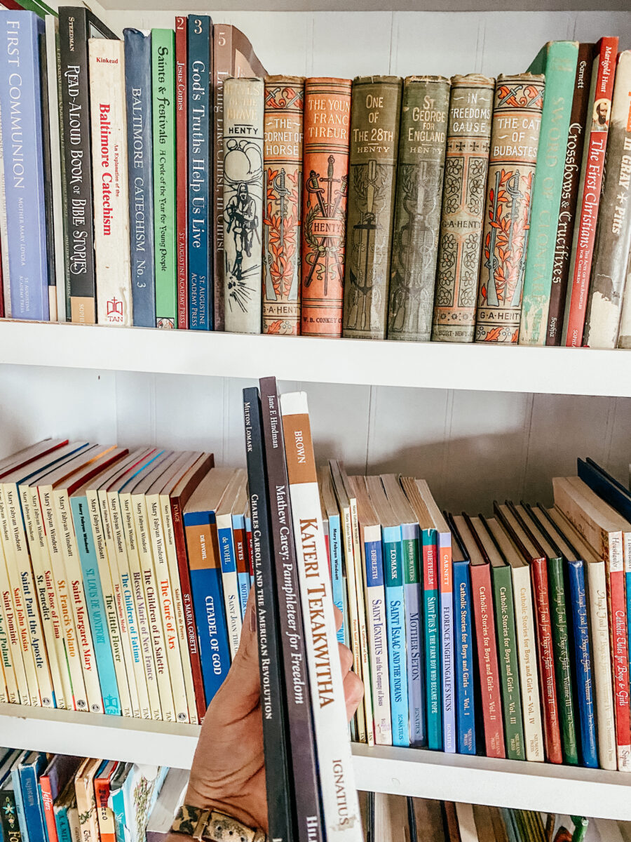 holding catholic biographies in front of a book shelf.
