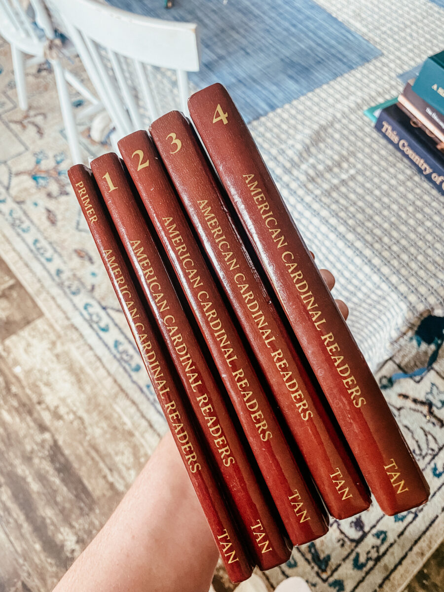 holding a stack of American Cardinal readers. 