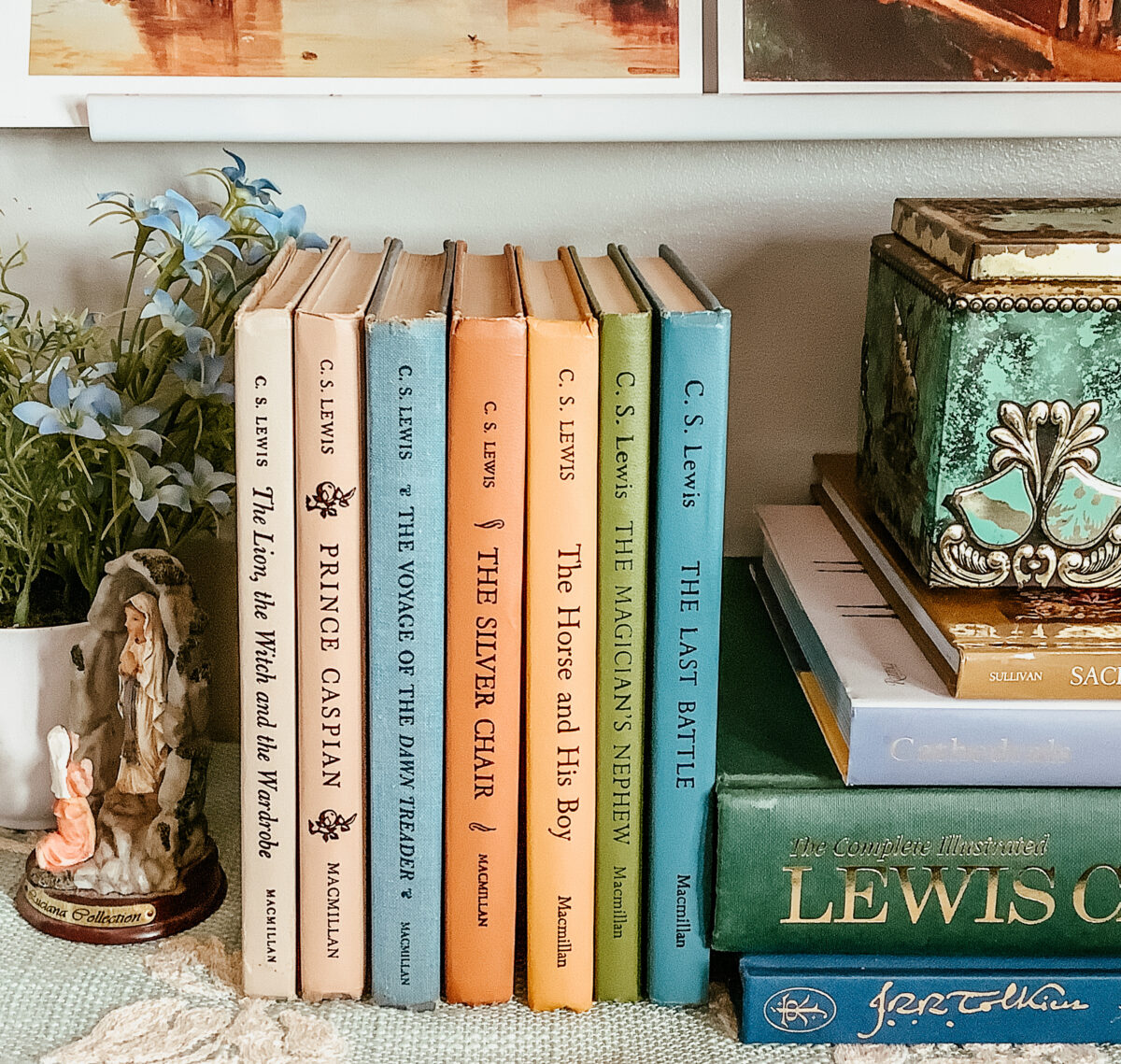 vintage Narnia books displayed on a shelf with a book stack to the side.