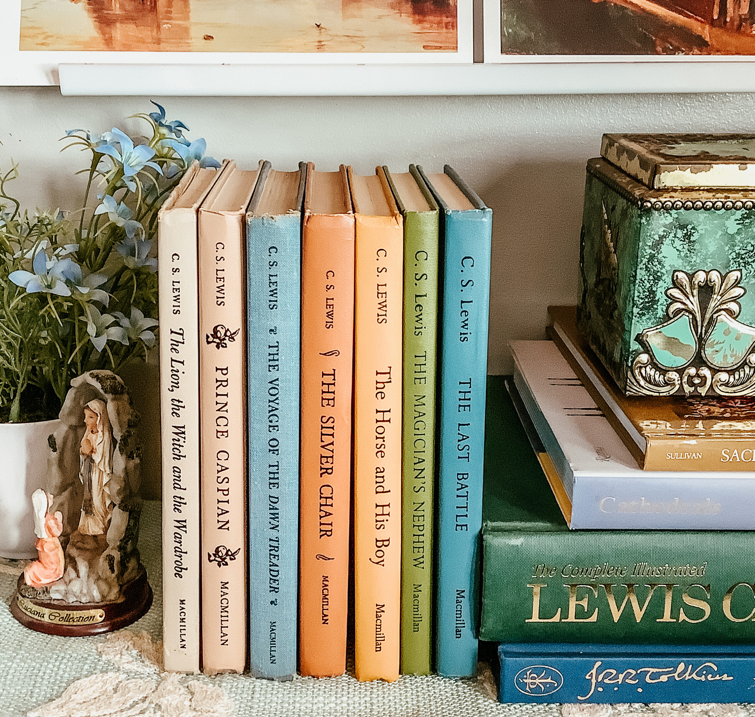 vintage Narnia books displayed on a shelf with a book stack to the side.