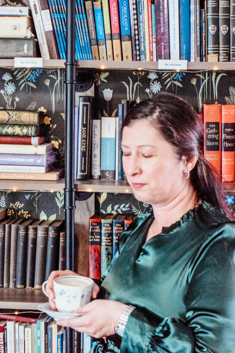 Mary standing in the home library with a cup of coffee.