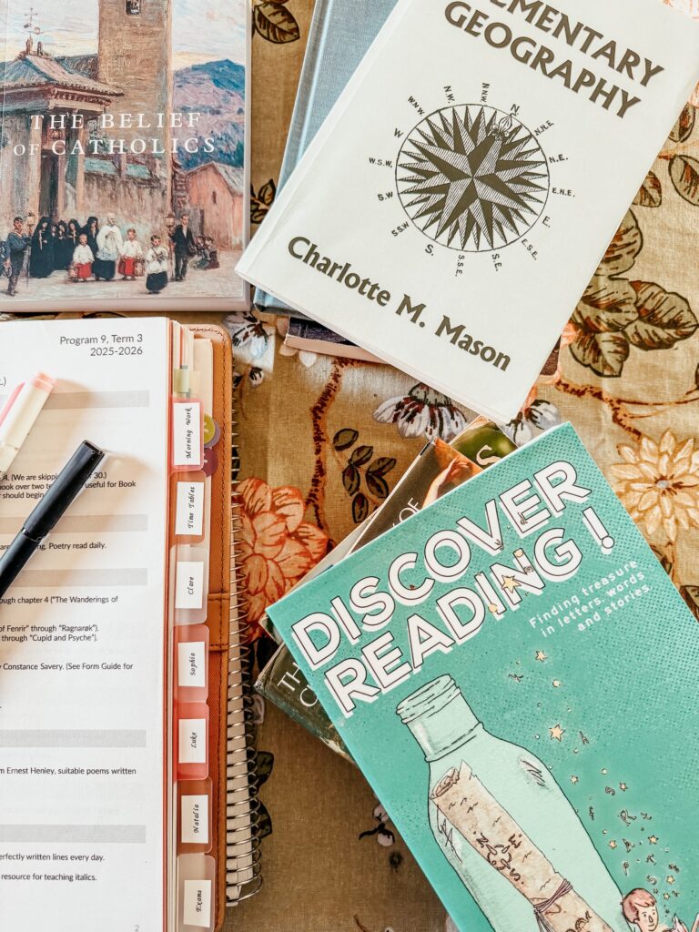 Stacks of school books and teacher planner on a table.
