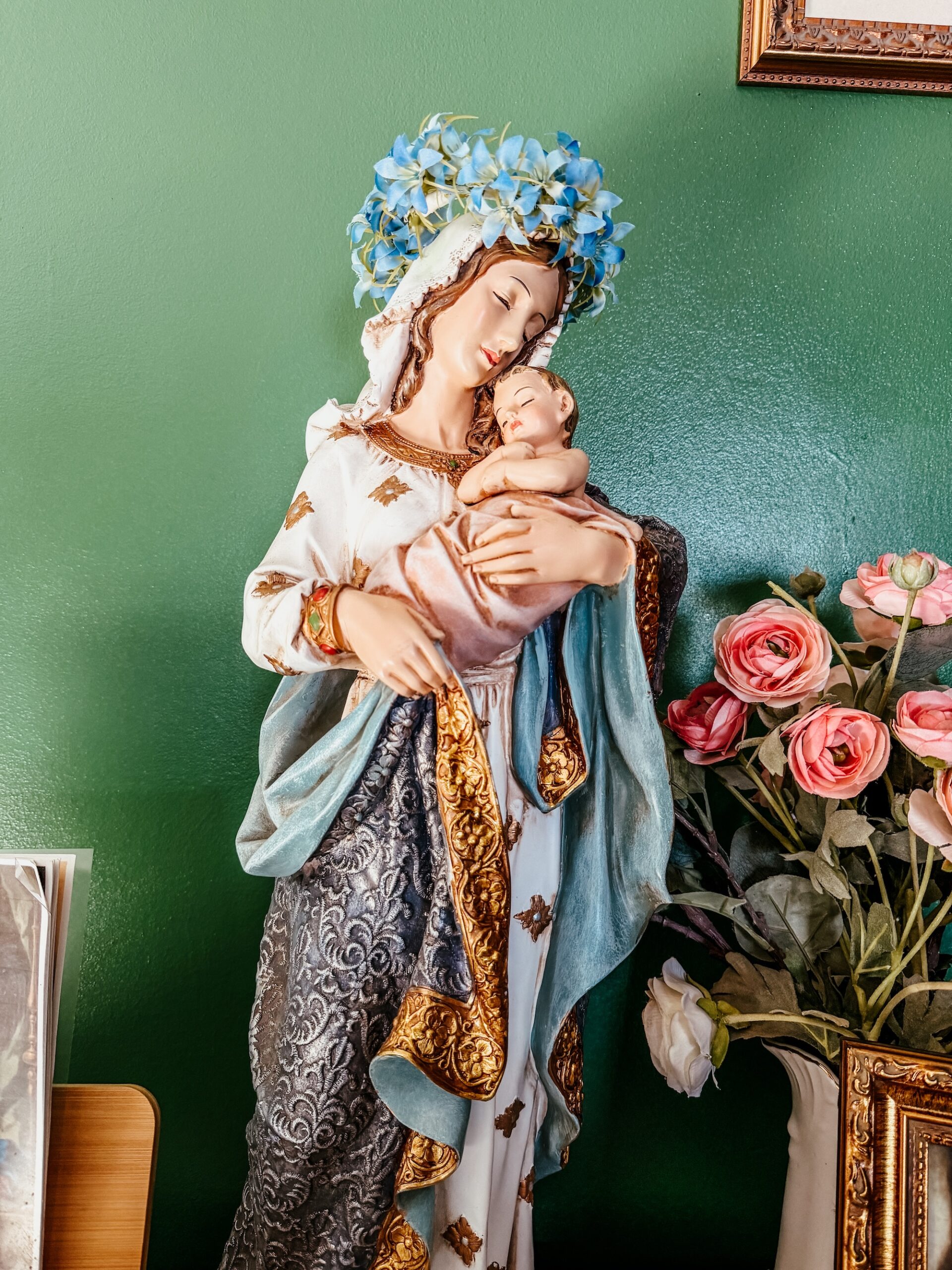 statue of the Blessed Mother holding the Child Jesus and she is crowned with flowers.