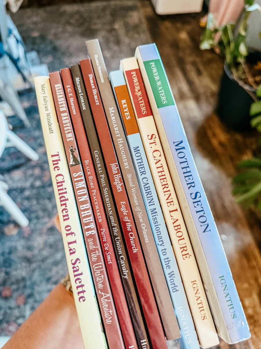 book stack of saint novels and catholic historical supplements.